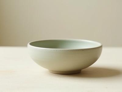 A simple, imperfect ceramic bowl on a wooden surface, embodying wabi-sabi aesthetic.